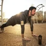 man in gray jacket doing push ups during sunrise